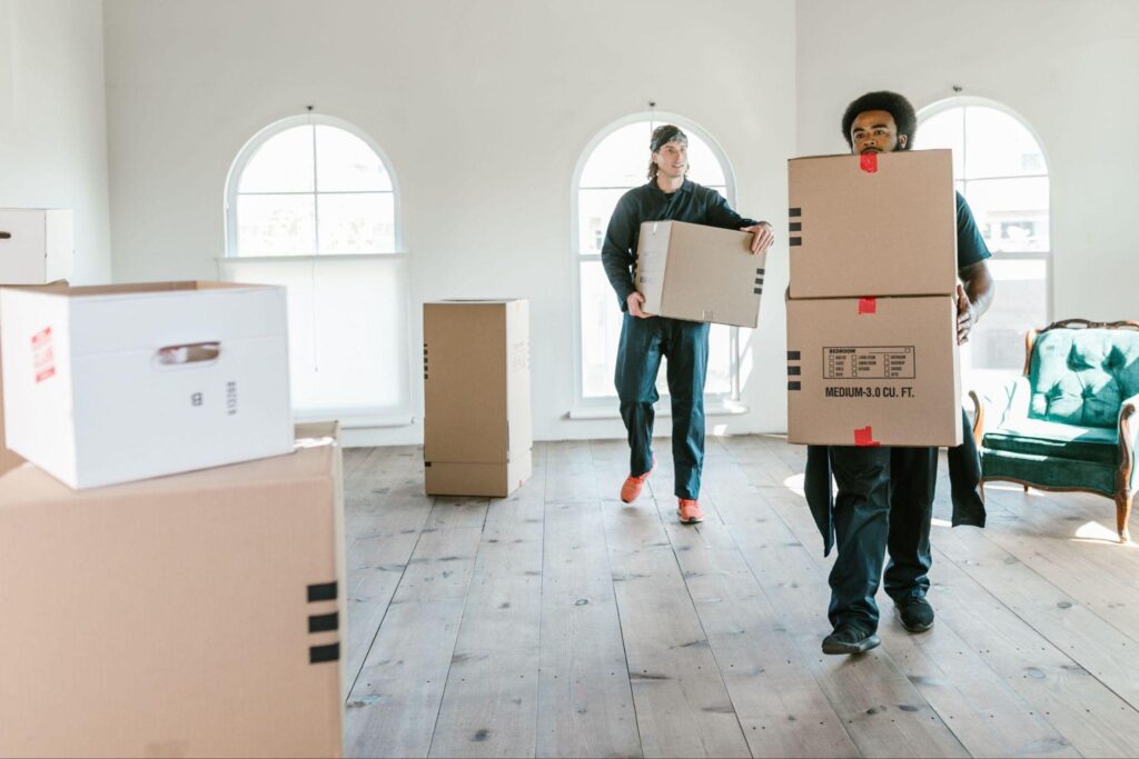 Calgary movers carrying labeled boxes into a bright, empty room during a household relocation.
